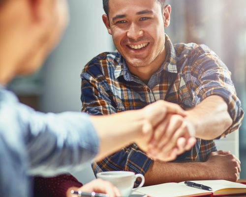 Shot of two young designers shaking hands together in an office.